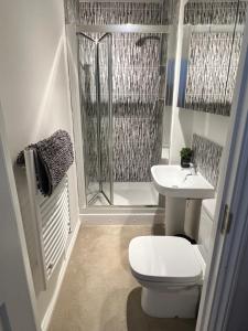 a bathroom with a toilet and a sink and a shower at Spacious 3-bed top-floor flat w/ balcony in Borehamwood