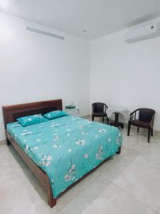 1 dormitorio con 1 cama con edredón azul y sillas en HOATEL MEKONG HOME GUESTHOUSE, en Can Tho