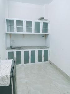 una cocina con armarios blancos y fregadero en HOATEL MEKONG HOME GUESTHOUSE, en Can Tho