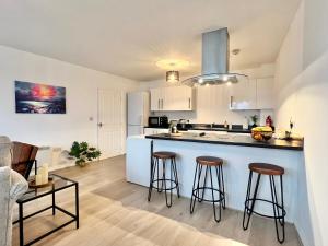 a kitchen with a counter and two bar stools at Families, Contractors, BIG bedrooms and Secure parking in Borehamwood