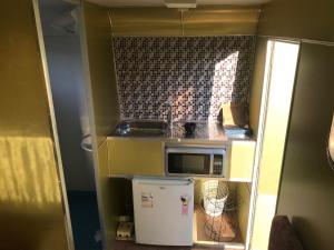 uma pequena cozinha com um lavatório e um micro-ondas em Trailer Refúgio Shakti em Florianópolis