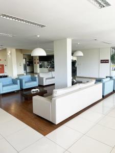 a lobby with white furniture and blue chairs at hihome - Metropolitan in Juiz de Fora