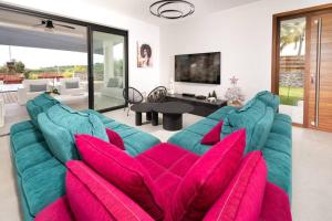 a living room with a blue couch with pink pillows at Summer View - Magnifique Villa neuve 10 personnes avec piscine miroir chauffée, jacuzzi intégré et vue mer idéalement située Chemin Summer in Saint-Gilles-les-Bains