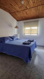 1 dormitorio con cama con sábanas azules y ventana en Esquel Centro en Esquel
