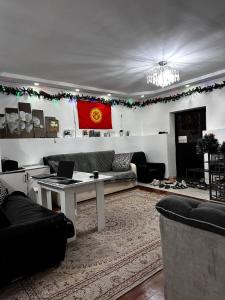 a living room with a couch and a table with a laptop at Nomadstan CAPSULE Hostel in Karakol