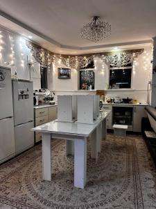 a large white kitchen with a white table and appliances at Nomadstan CAPSULE Hostel in Karakol