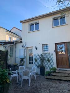 a white house with a table and chairs in front of it at Maison de charme avec jardin à 10mn de Paris in Nanterre