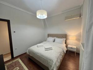 a white bedroom with a bed and a lamp at SKG City Center Apartment in Thessaloniki