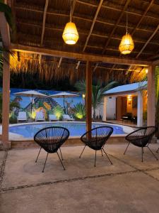 3 chaises assises en face d'une piscine dans l'établissement CASA VICTORIA, à Chichén Itzá