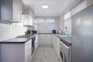 a white kitchen with a sink and a dishwasher at Chic & Peaceful Nook at Clifton Road, Sleeps 5 in Darlington