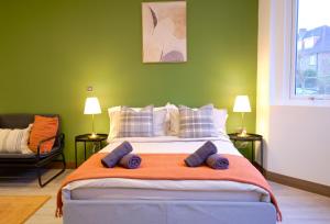 ein grünes Schlafzimmer mit einem großen Bett mit blauen Kissen in der Unterkunft GoldersGreen Apartments by Sleepy in London