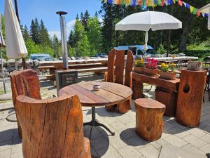 einen Holztisch mit Stühlen und einem Sonnenschirm in der Unterkunft Hôtel Restaurant du Marchairuz in Le Brassus