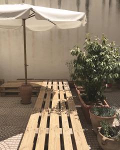 einer Holzbank mit Regenschirm und Topfpflanzen in der Unterkunft Appartamento-Studio con cortile in Trapani