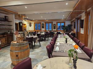 a restaurant with tables and chairs and a wine barrel at Hôtel Restaurant du Marchairuz in Le Brassus