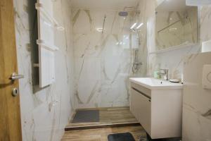 a white bathroom with a sink and a shower at Apartment Vista In Prestige in Zlatibor