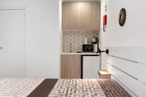 eine kleine Küche mit einem Bett und einer Mikrowelle in der Unterkunft Apartamento Mar in Moncarapacho