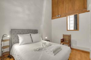 een wit bed met witte handdoeken in een slaapkamer bij L'encrier - Appt confortable pour 2 in Toulouse
