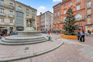 een fontein midden in een stad met een kerstboom bij L'encrier - Appt confortable pour 2 in Toulouse