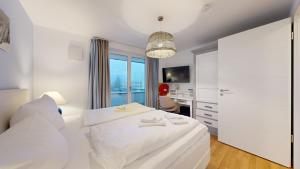 ein weißes Schlafzimmer mit einem Bett und einem Schreibtisch in der Unterkunft strandnahe FeWos mit Terrasse oder Dachterrasse, Strandhaus Seeblick, Binz in Binz