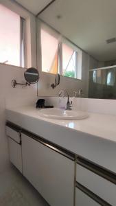 a bathroom counter with a sink and a mirror at Casa com piscina a 800 metros da praia de Buraquinho in Lauro de Freitas