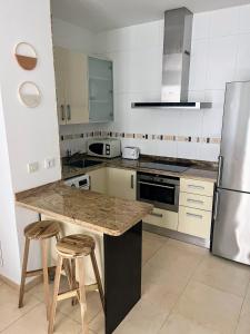 a kitchen with a counter with stools and a refrigerator at Apartamento 1ª línea Patacona in Valencia