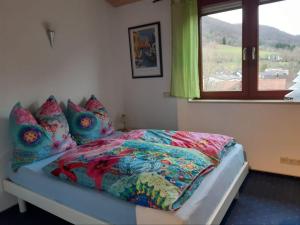 Un dormitorio con una cama con un edredón colorido y una ventana en Sterngässle, en Deggingen