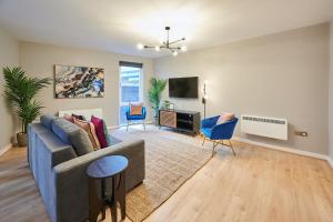 ein Wohnzimmer mit einem blauen Sofa und Stühlen in der Unterkunft Host & Stay - Ropewalks Quarters in Liverpool