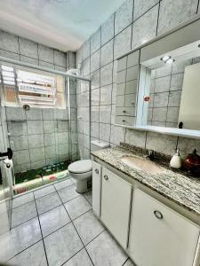y baño con aseo, lavabo y espejo. en Flat da Graça, en Palhoça