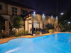 - une grande piscine en face d'une maison la nuit dans l'établissement My Home Pool Villa Hatyai, à Hat Yai