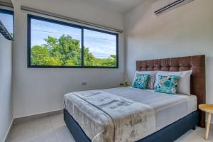 - une chambre avec un lit et une grande fenêtre dans l'établissement Muna Santa Rosa Apartamentos, à Tamarindo