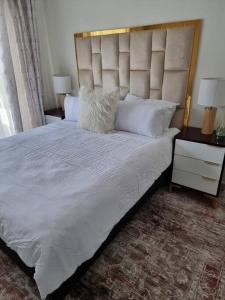 1 dormitorio con 1 cama grande con sábanas y almohadas blancas en Crestline2 at Emeraldskye en Lombardy East