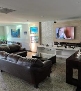 a living room with couches and a flat screen tv at Loft Prainha 101, arraial do cabo in Arraial do Cabo