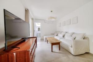 a living room with a white couch and a flat screen tv at NOCNOC - Le Zellige - Petite piscine et jardin en ville in Montpellier