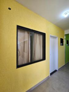 a yellow wall with a window in a room at Mini Casa 02 em Cabo Frio in Cabo Frio