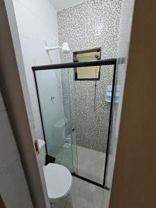 a bathroom with a toilet and a glass shower at Mini Casa 02 em Cabo Frio in Cabo Frio