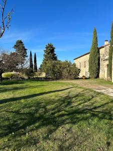 un gran patio de césped con un edificio y árboles en Chambres d'hôtes - Le Mas du Colombeyras en Espeluche