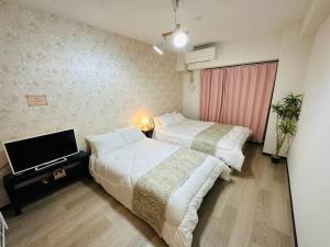 大阪市にある202 黒門市場1分!道頓堀まで徒歩8分!心斎橋まで徒歩9分!のベッド2台とテレビがあるホテルの部屋