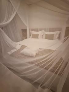 1 dormitorio con 1 cama con sábanas y almohadas blancas en Hotel Boutique Vila São João, en Trancoso