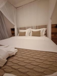 a bedroom with a large bed with white sheets and pillows at Hotel Boutique Vila São João in Trancoso