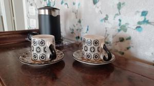 deux tasses à café et des soucoupes sur une table en bois dans l'établissement B&B Opera Prima, à Vérone