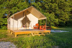 a tent with a wooden deck in a field at Couple's Glamping Tent - Roaring River in Cassville