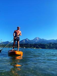 Un homme sur une planche de paddle dans l'eau dans l'établissement seehaus ausZEIT, à Faak am See