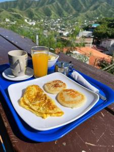 a plate of pancakes on a table with orange juice at Tamarindo Beach hostel in Taganga