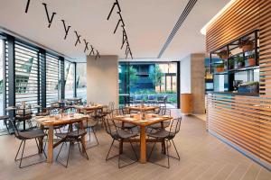 a restaurant with wooden tables and chairs and windows at Four Points by Sheraton Sydney, Central Park in Sydney