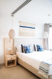 a white bedroom with a large bed with blue pillows at Can Salia in San Antonio Bay
