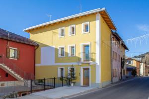 une maison jaune dans une rue avec des maisons colorées dans l'établissement Begale - Rifugio Urbano, à Rotzo