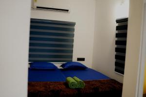 a bedroom with a bed with blue pillows and slippers on it at Summer beach house Alleppy beach in Alleppey