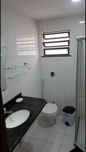 a bathroom with a sink and a toilet and a window at Loft Prainha in Arraial do Cabo