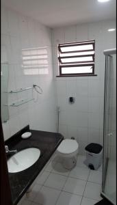 a bathroom with a sink and a toilet and a window at Loft Prainha 101, arraial do cabo in Arraial do Cabo