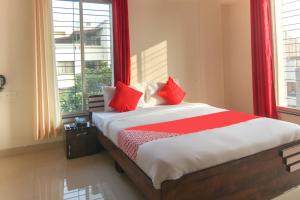 a bed with red pillows in a room with a window at Hotel Felicita Airport Inn in Pune